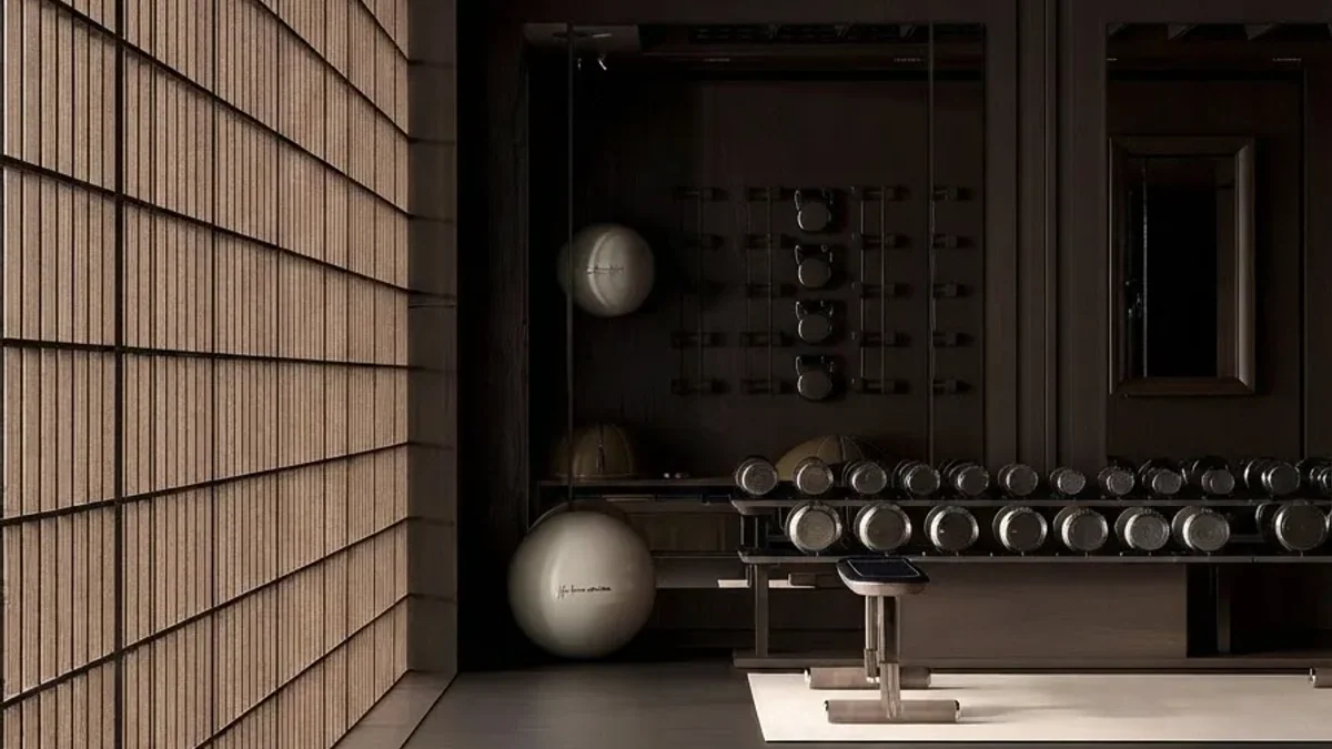 Basement home gym with backlit wood lattice wall panels, dark walls, a long rack of dumbbells, an adjustable bench, exercise balls and a pale rubber floor zone