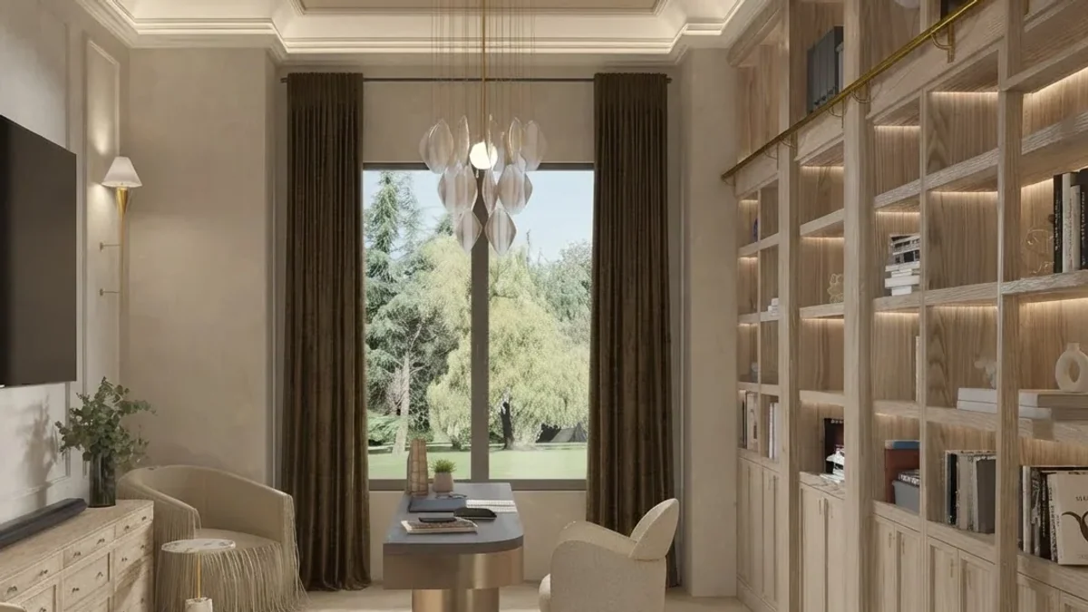 Home office design with floor to ceiling pale oak library shelving with a brass rail, a rounded desk under a tall window with dark velvet curtains, a cream boucle chair and a glass petal chandelier