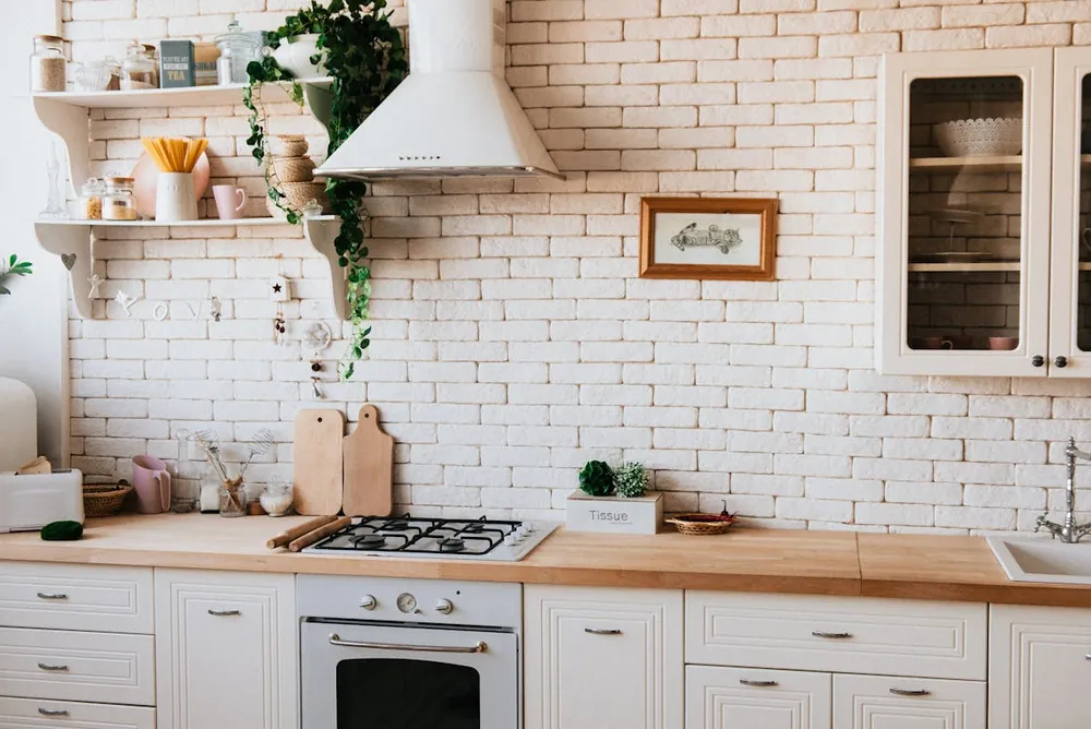 Farmhouse AI kitchen design with shaker cabinets, a range hood and warm brick