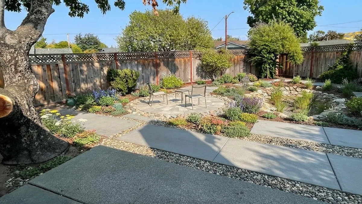 The base backyard rendered with no lawn, large pavers, gravel, sedum and salvia beds, a seating circle and a rain garden corner