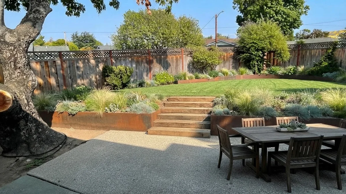 The base backyard rendered with two corten steel terraces, timber steps, a lower dining patio and an upper lawn