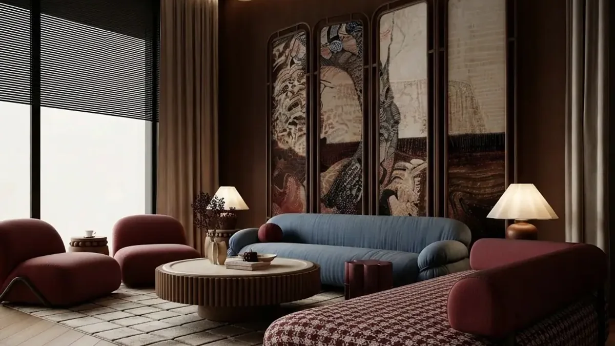 Warm dark living room with a blue rounded sofa, burgundy lounge chairs, a burgundy houndstooth daybed, a fluted round coffee table, two table lamps with cream shades and a four panel painted folding screen on the back wall above a herringbone floor