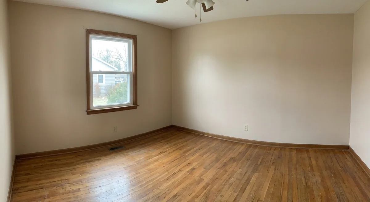 The same living room cleared to an empty space by AI, keeping the same window, wood floor, and proportions, ready to be redesigned
