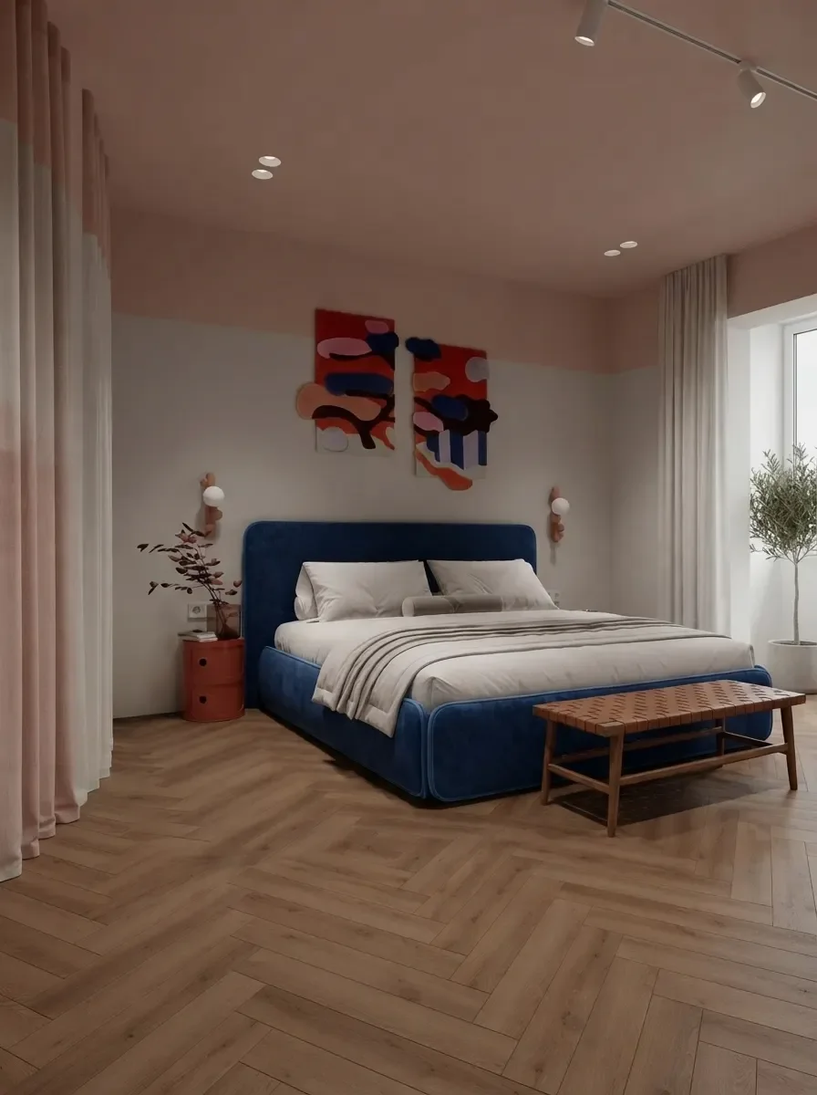 The same small blush bedroom from the door, showing the navy bed on the wall facing the door, a slim bench at its foot and the walkway kept along one side