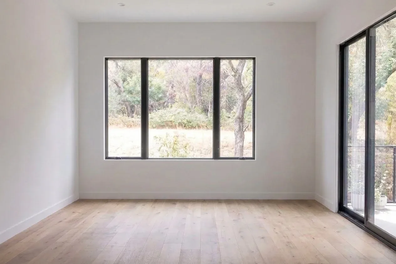 Empty room with large windows and hardwood floors before AI home design