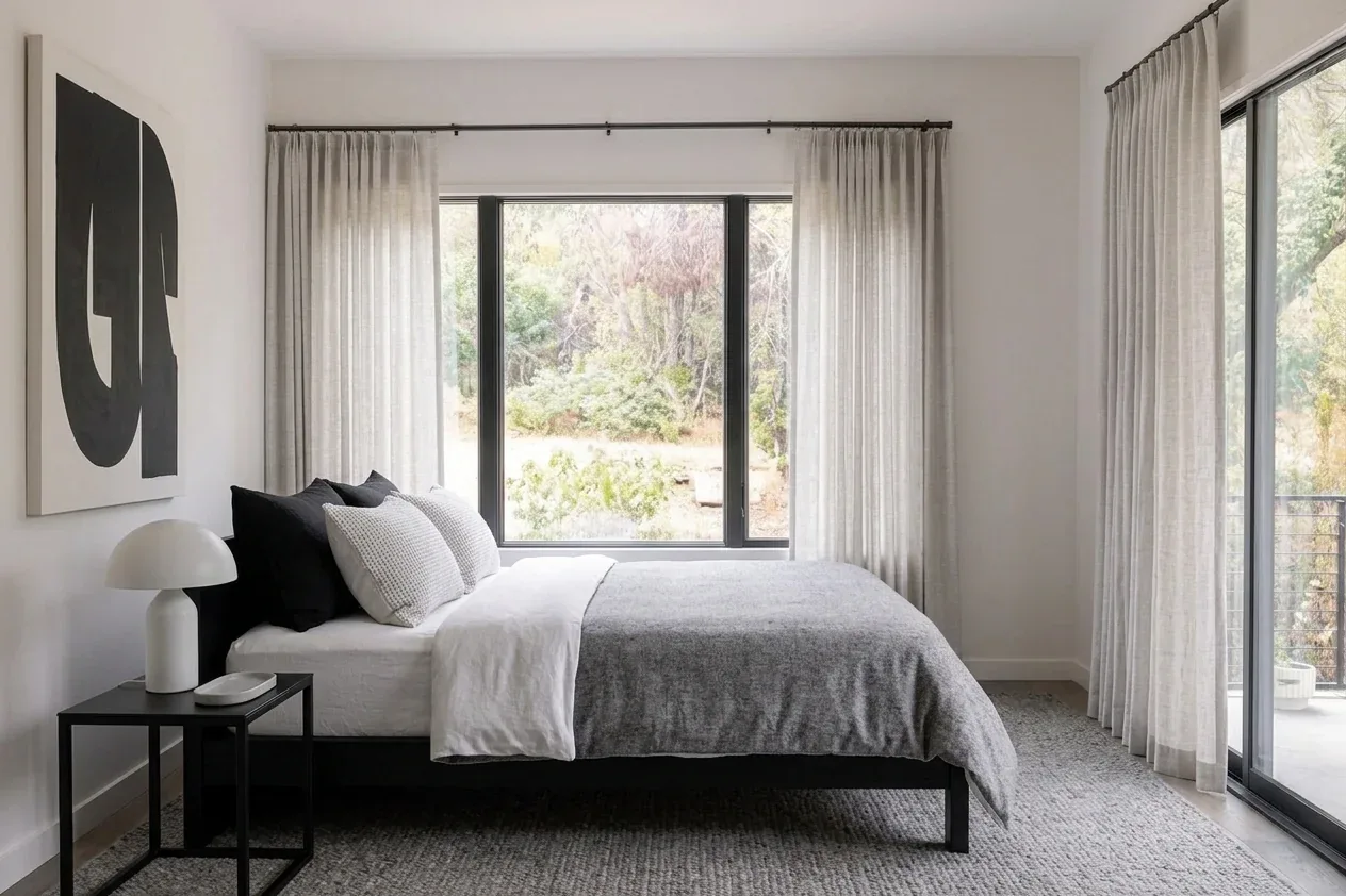 AI-designed modern bedroom with platform bed, grey bedding, black accents, and sheer curtains