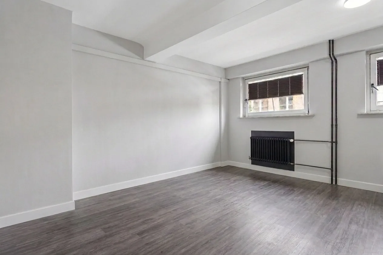 Empty city apartment with dark hardwood floors, exposed pipes, and small windows — the starting point for 47 interior design ideas