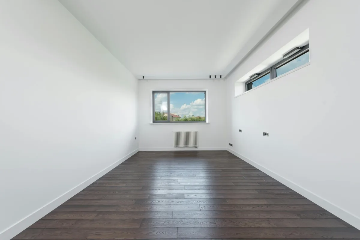 Empty apartment with white walls and dark hardwood floors waiting to be furnished