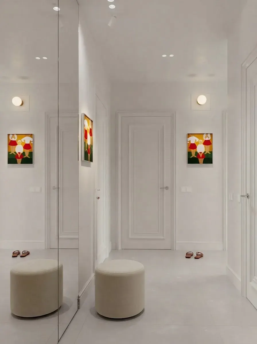 White entry hall render with two separate panelled interior doors on one wall, a mirrored panel between them and two framed prints