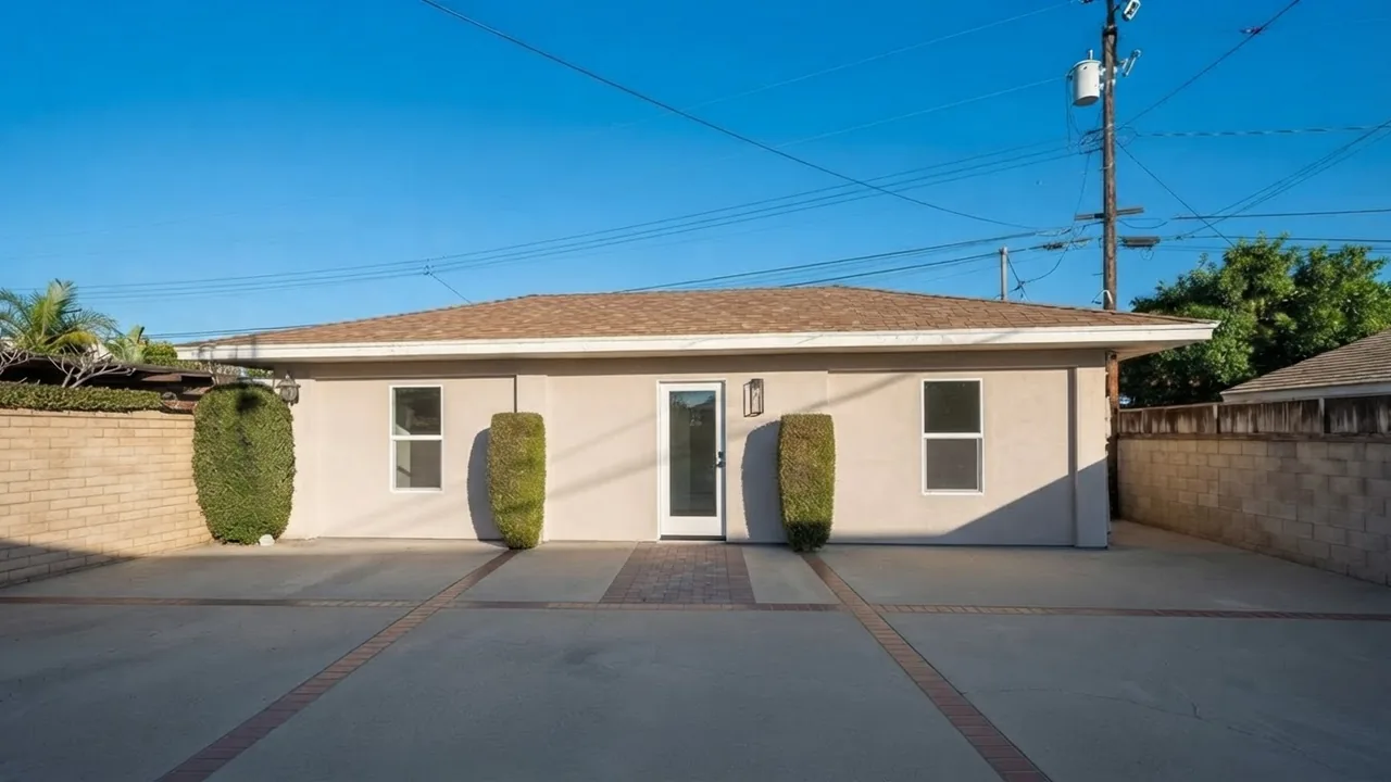 The same three-bay garage re-rendered as a finished accessory dwelling unit, the garage doors replaced by matching stucco wall with two tall windows, a glazed entry door and a paved path