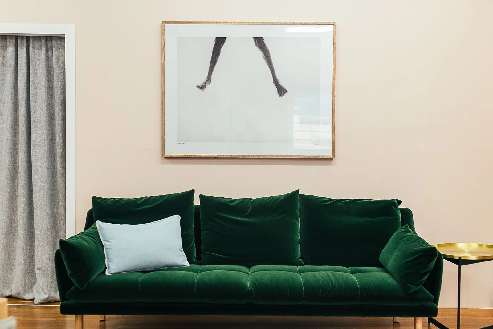 A bright living room redesigned into a warm modern space with a green velvet sofa, alcove shelving and layered natural light