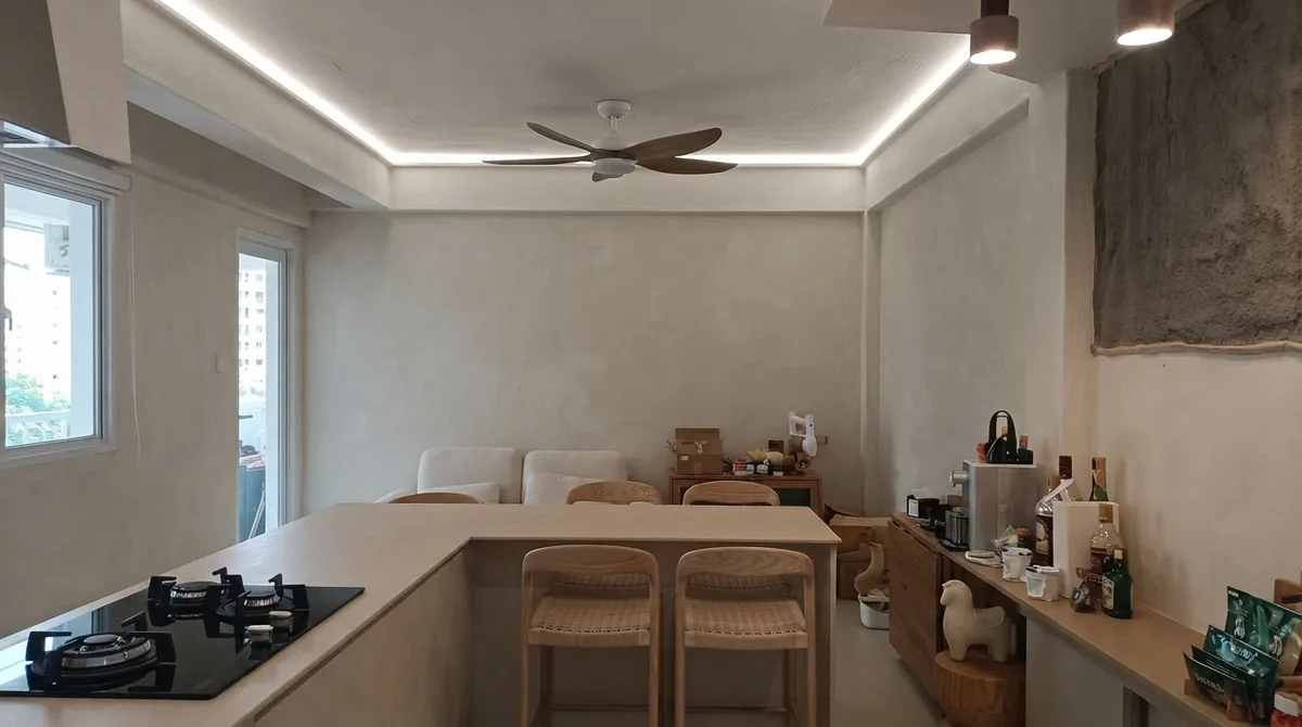 Open kitchen in a real renovated flat with pale grey limewashed walls and a deliberately exposed patch of rough render above the island