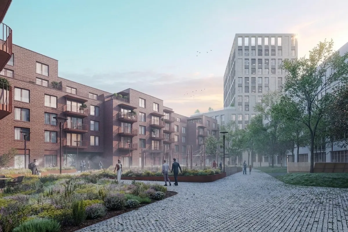 YIT Zwirn Bratislava courtyard at sunset with golden light warming brick facades, green balcony terraces, and residents on cobblestone walkways