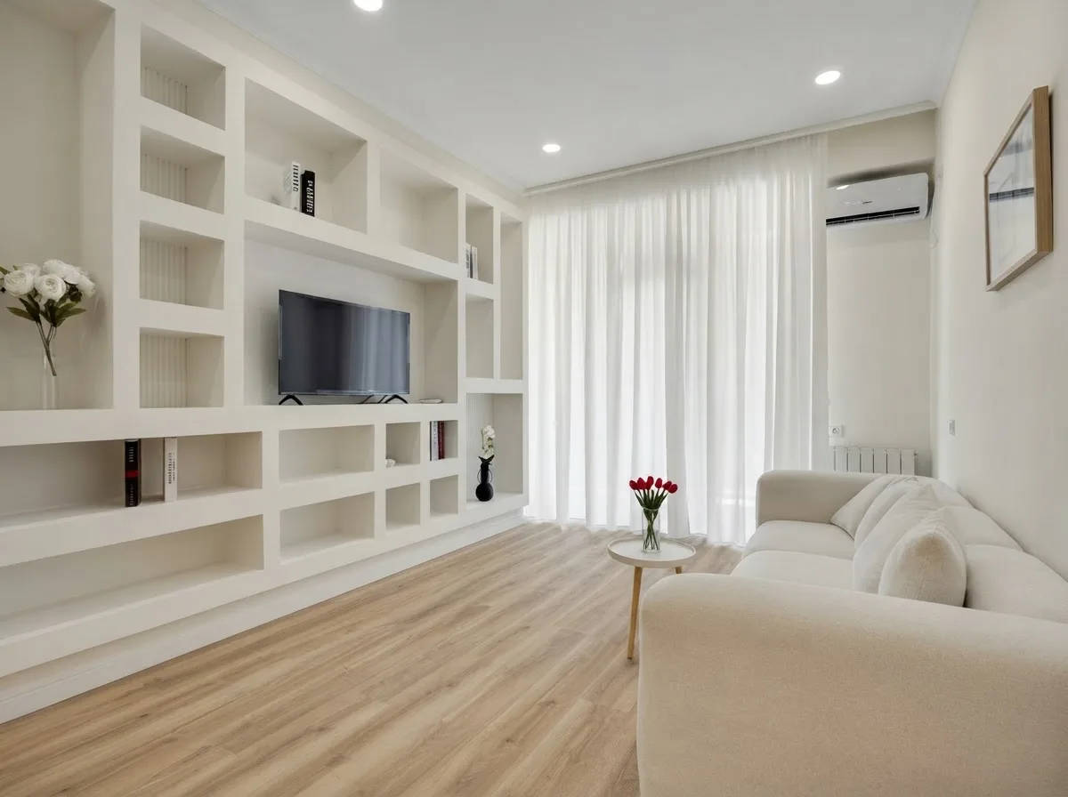 Real photograph of a living room with a white built in shelving wall, a TV and a pale sofa, walls in Alabaster