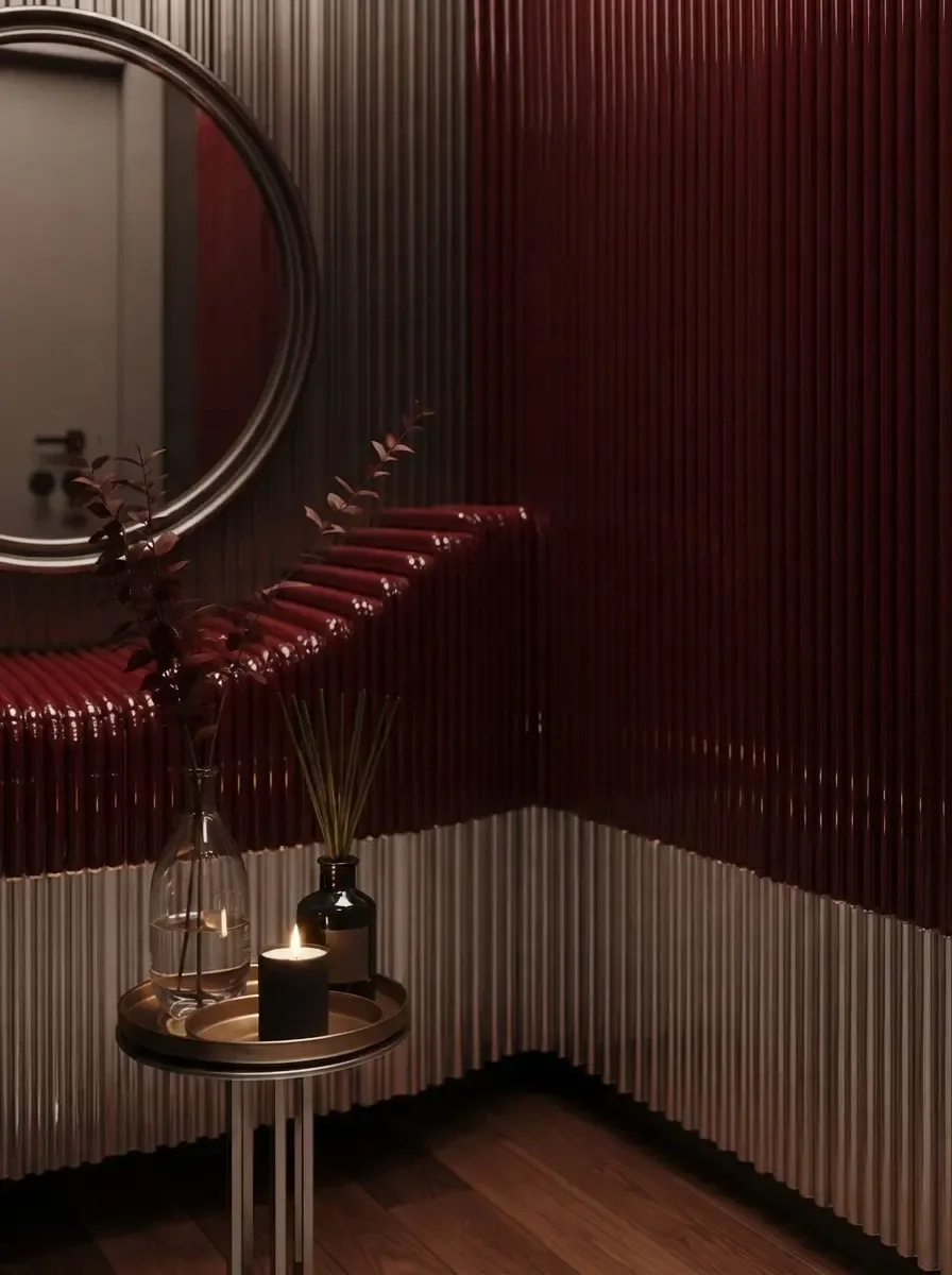 Dramatic small powder room render with a tall arched mirror on dark plaster walls, rippled red glass counter and a wall-hung basin, warm side lighting