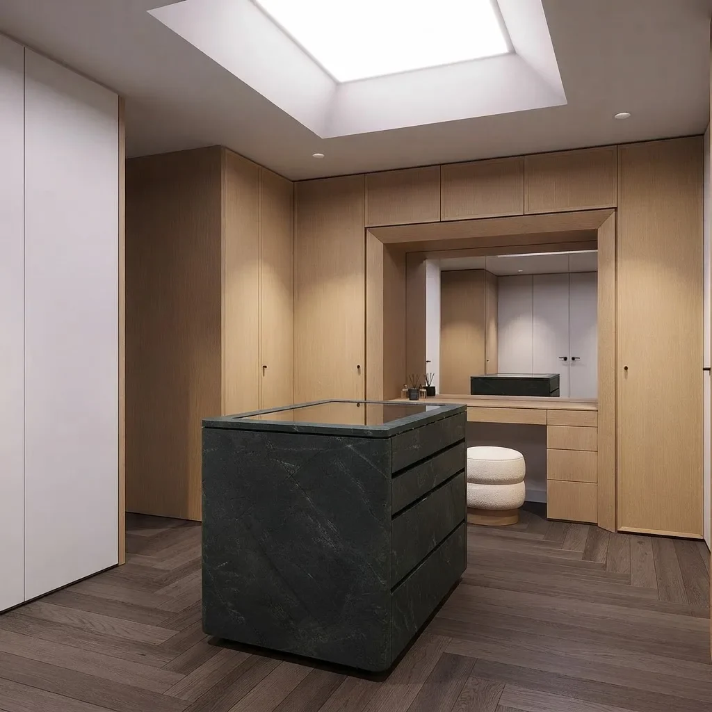 A minimalist walk-in closet under a skylight with pale oak wardrobes on three walls, white doors and a green marble island