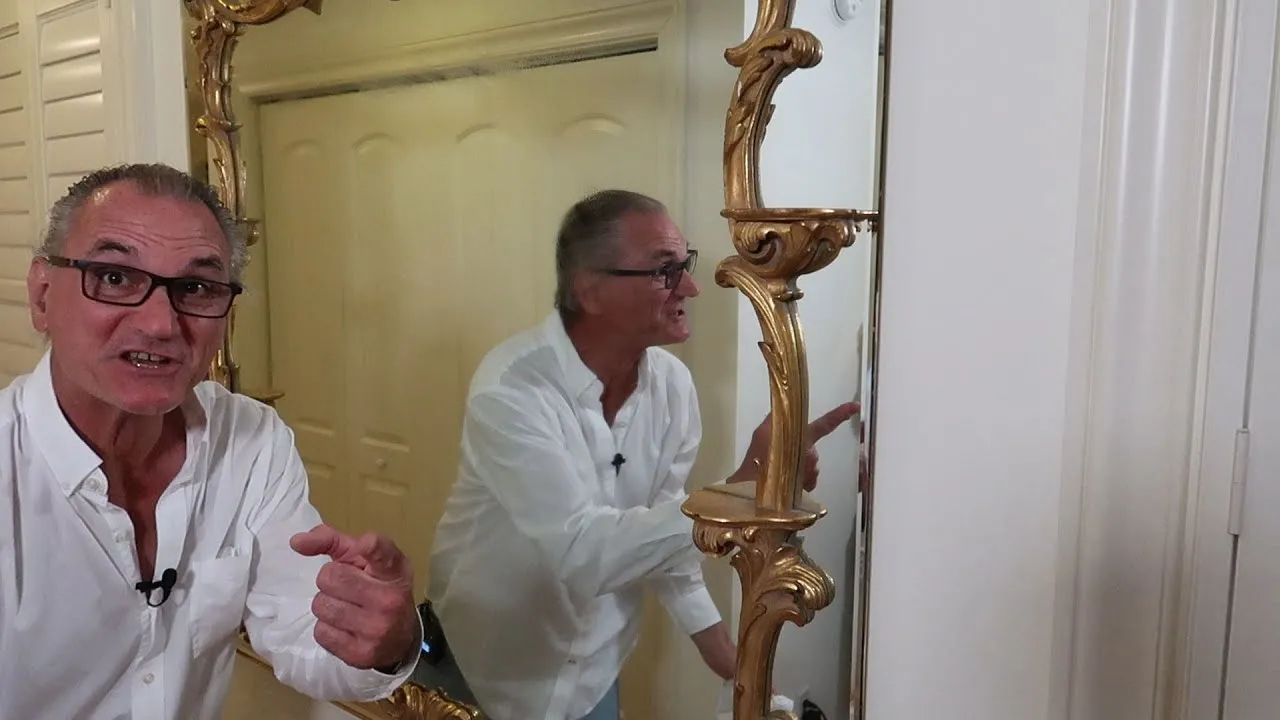 A heavy framed mirror being mounted on a drywall wall with a French cleat, from Steve's Stray Stuff tutorial video