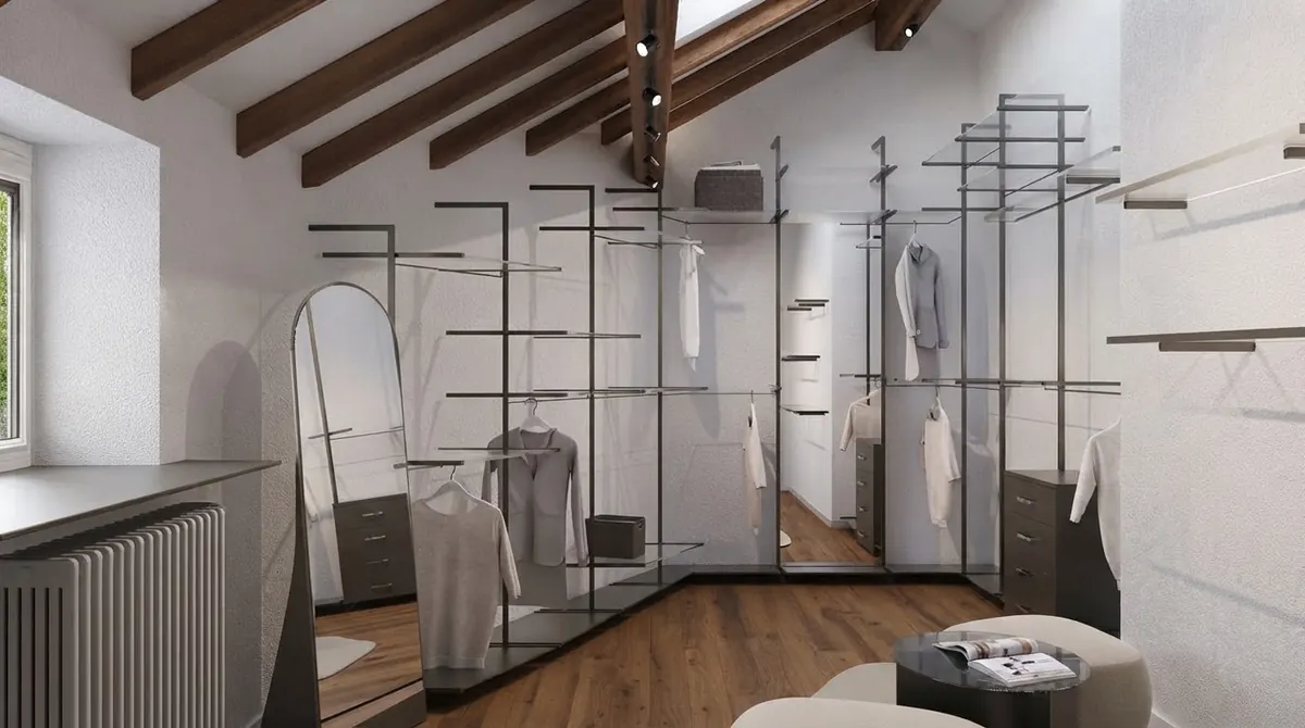 Barndominium loft under exposed dark timber beams used as an open dressing room, with steel clothing rails, a full length arched mirror and a pale timber floor