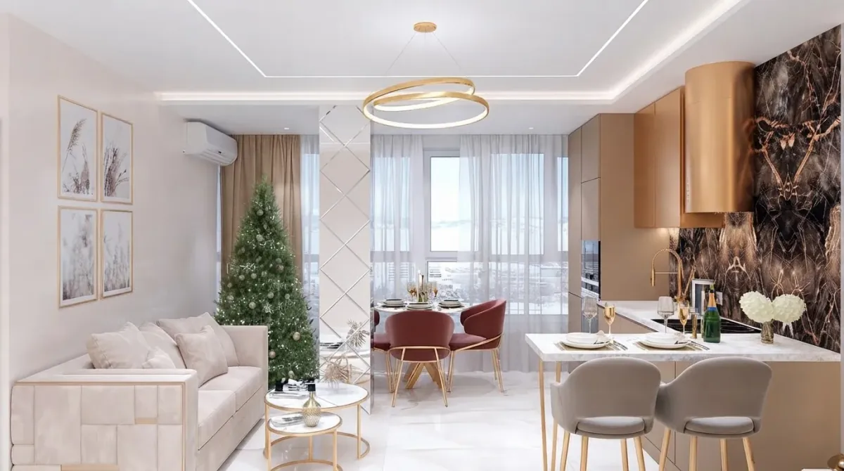 Bright open plan apartment with a green Christmas tree at the balcony door, a cream sofa, a round dining table with blush velvet chairs, a marble kitchen with a copper hood and a gold ring chandelier