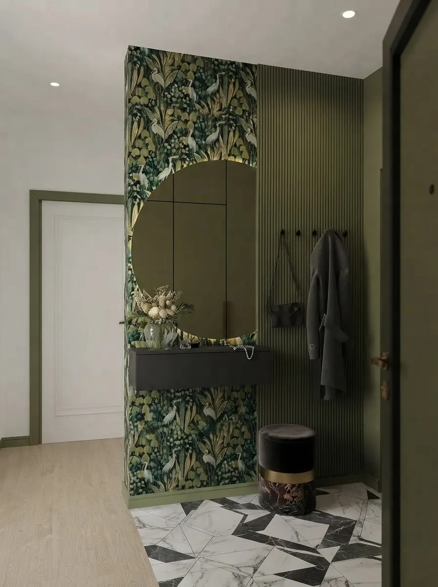 Mudroom with a dark green botanical leaf wallpaper on a wall section around a round mirror, olive green fluted paneling, coat hooks and a black and white geometric tile floor