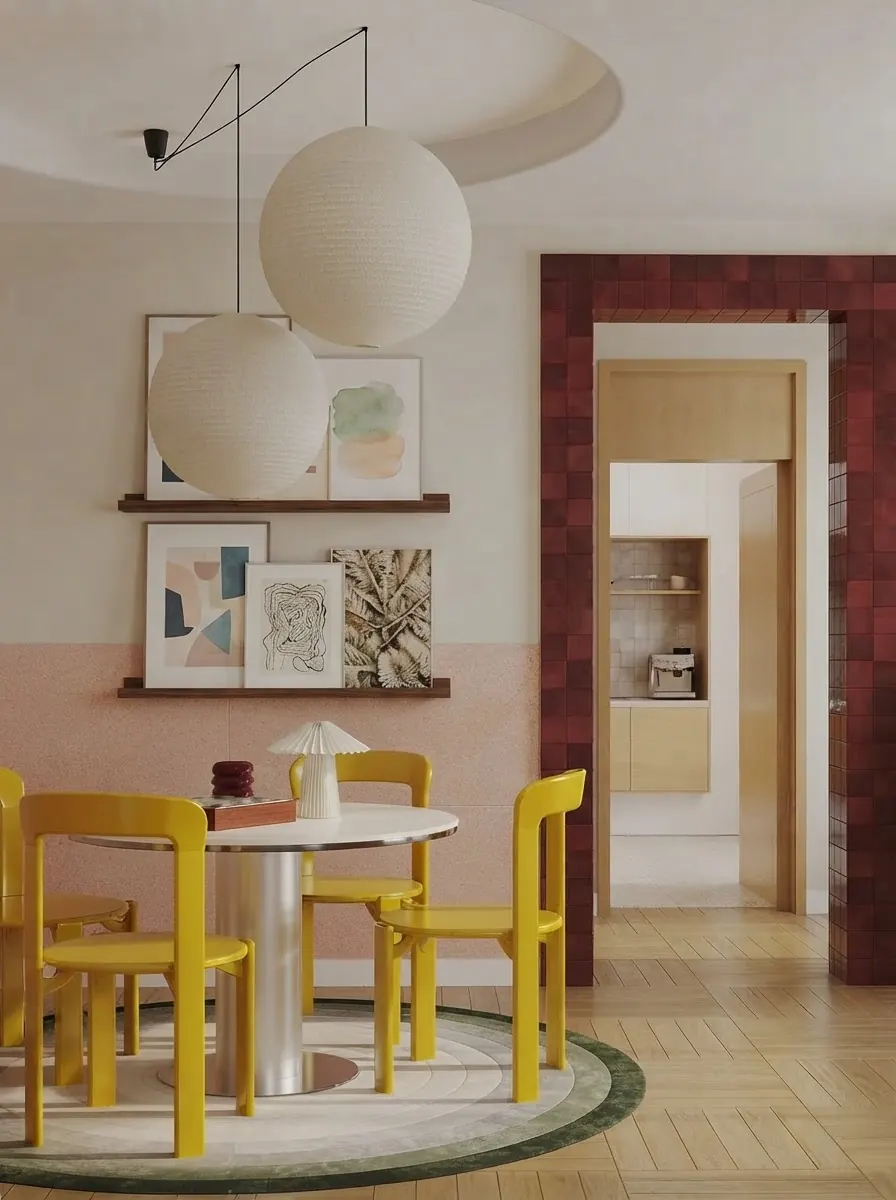 Dining room with yellow chairs, a round white table and two oak picture ledges holding overlapping abstract prints against a pale pink wall