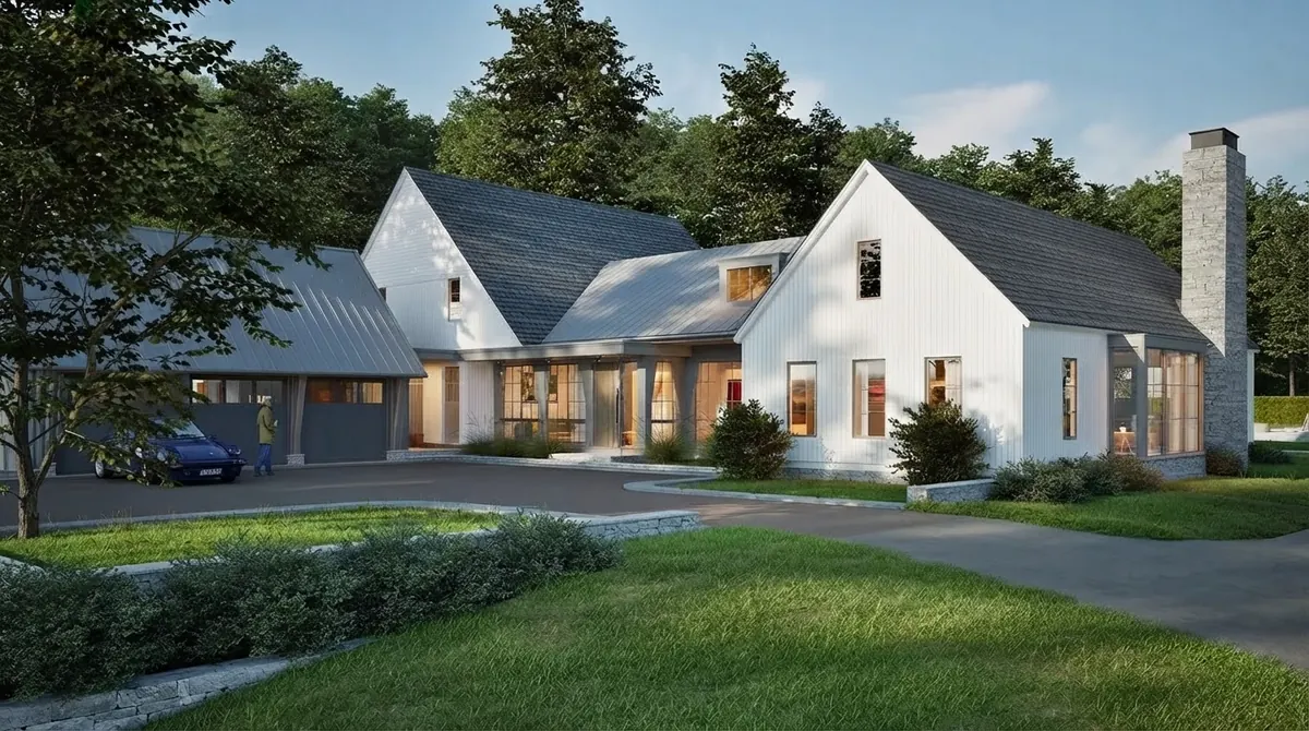 White board and batten farmhouse built as connected gabled wings with grey roofs, a tall stone chimney, warm lit windows and a curved driveway in front